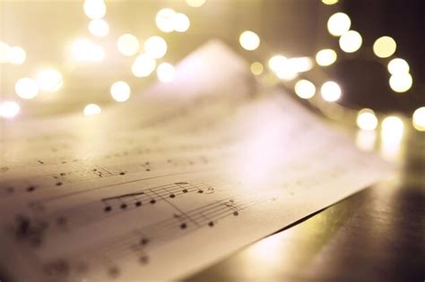 Premium Photo | Old sheet with christmas music notes as background against blurred lights ...