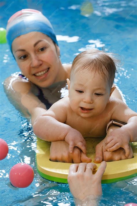 Premium Photo | Baby with mother trainer in indoor swimming pool having ...