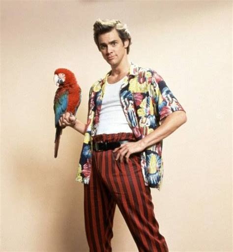 a man holding a parrot in his hand while standing next to a wall with a clock on it