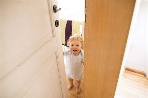 Portrait of happy baby boy opening the door stock photo