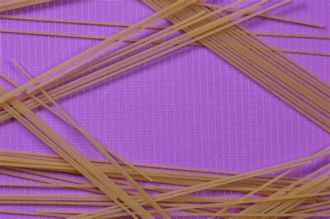 Premium Photo | Raw spaghetti on a purple background Vegetarian food concept Closeup of an ...