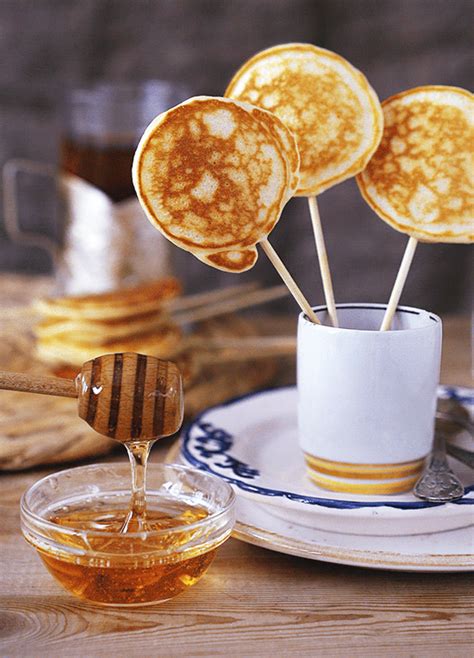 honey syrup being poured into a cup with four pancakes on the stick in front of it
