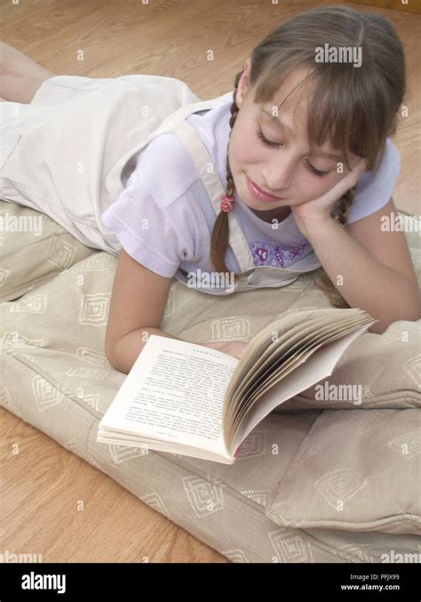 Girl lying down and reading book Stock Photo - Alamy