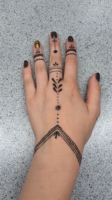 a woman's hand with tattoos on it and two fingers in the shape of arrows