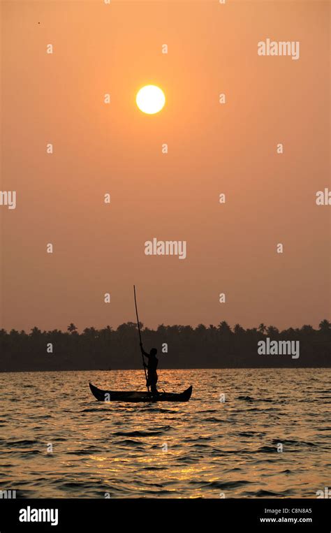 Vertical shot of sunset on Vembanad Lake, Kerala , India with boatman ...