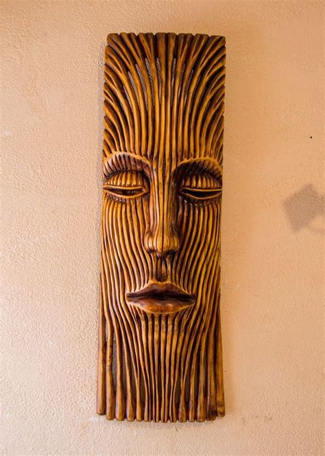 a carved wooden face mounted to the side of a wall next to a light fixture