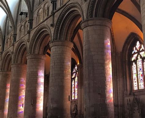 Inside Gloucestershire cathedral on a sunny day. Stained glass lighting up the pillars ...