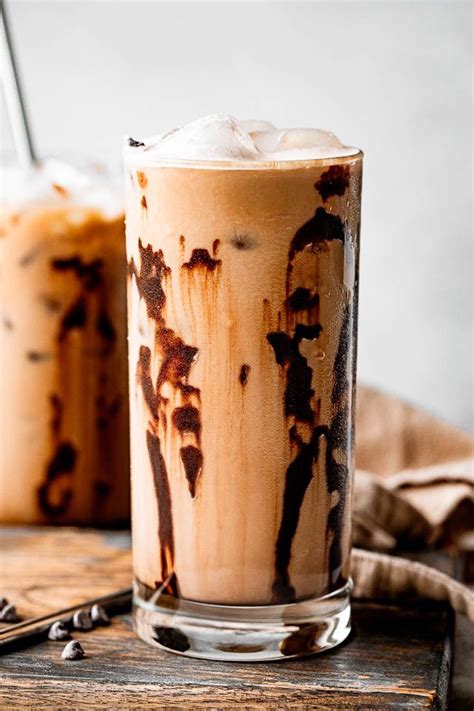 two glasses filled with iced coffee sitting on top of a wooden table