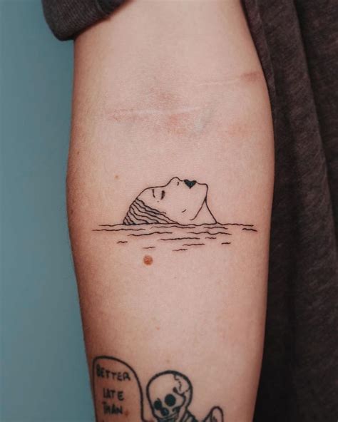 a person with a tattoo on their arm that has a skull in the water and an iceberg behind it