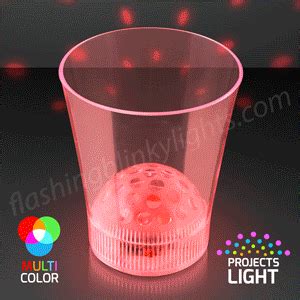a pink plastic cup sitting on top of a black table next to a red light