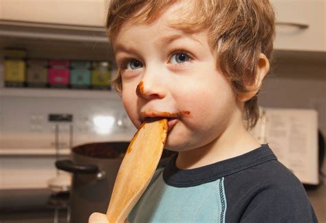 A Boy Licking A Spoon With Chocolate On His Face; Langley, British Columbia, Canada, Chocolate ...