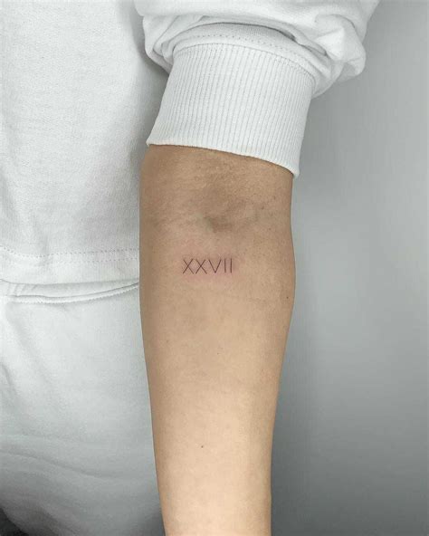 Roman numerals XXVII tattoo by Conz Thomas inked on the left forearm ...