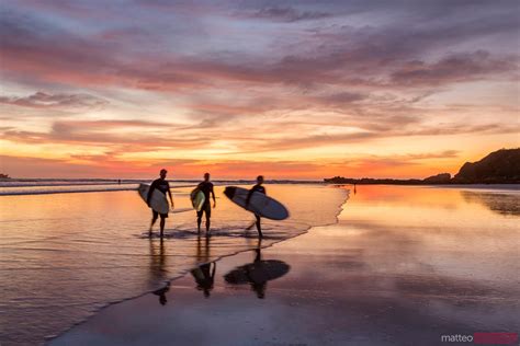 - Surfers at sunset walking on beach, Playa Guiones, Costa Rica | Royalty Free Image