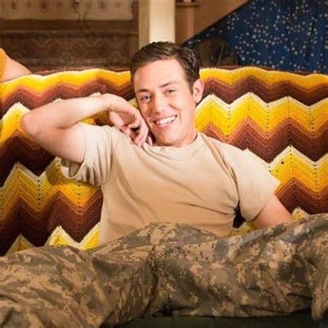 a young man sitting on top of a couch next to a person in camouflage pants