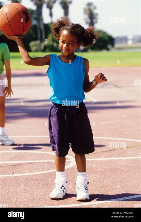 A young black girl playing basketball in a park Stock Photo - Alamy