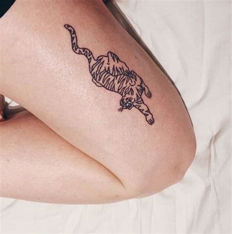 a woman laying on top of a bed with a tattoo on her arm and leg