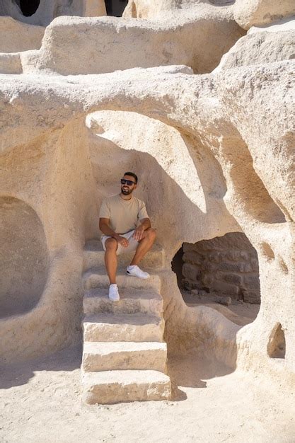 Premium Photo | Tourist with beard and sunglasses sitting on stairs inside the famous uchisar ...