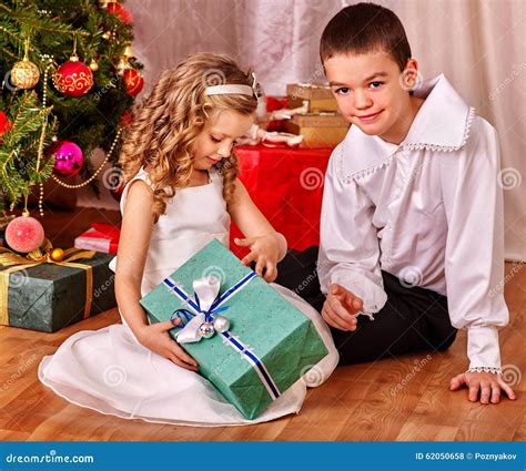 Children Receiving Gifts Under Christmas Tree Stock Photo - Image of sibling, sister: 62050658