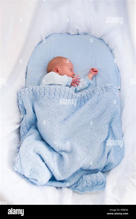 Newborn baby boy in bed. New born child sleeping under a blue knitted blanket. Children sleep ...