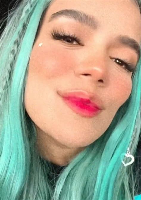 a woman with green hair and pink lipstick looks at the camera while she is taking a selfie