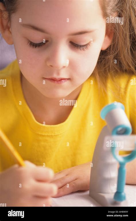 Young girl writing home school studying with microscope Stock Photo - Alamy