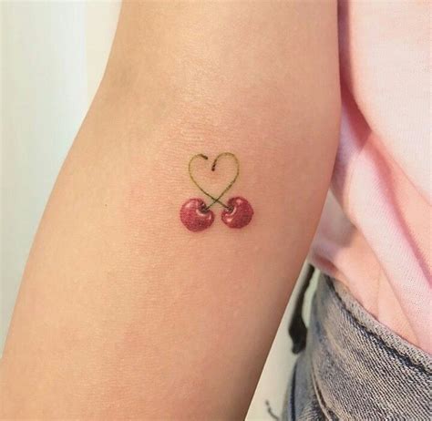 two cherries in the shape of a heart tattoo on the left forearm and right arm