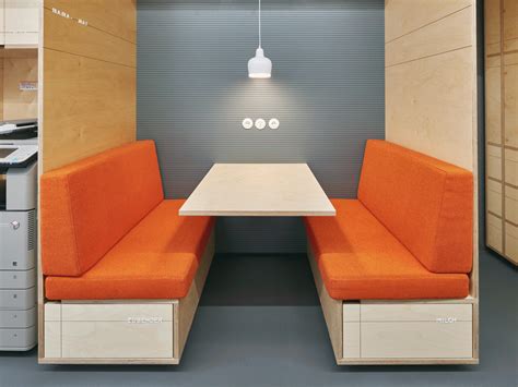 an orange couch sitting next to a white table in a room filled with cabinets and drawers