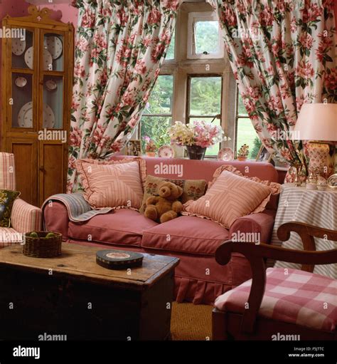 Floral curtains on window behind a pink sofa in country living room ...