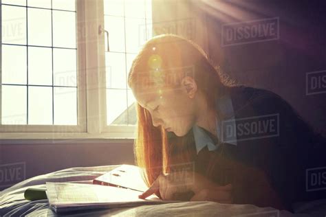 Teenage girl reading in bed - Stock Photo - Dissolve