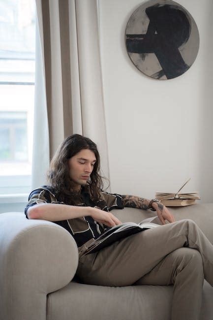 A Man Reading Book while Sitting on a Bed · Free Stock Photo