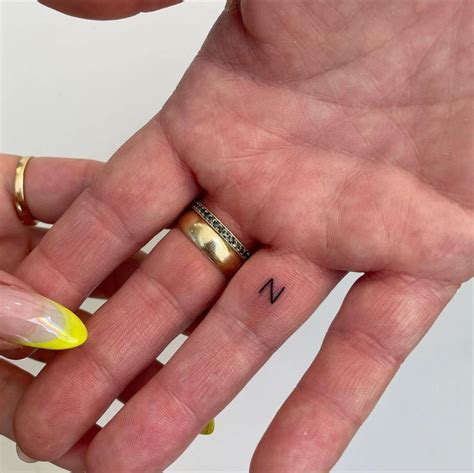 Minimalistic letter "N" tattoo located on the finger.
