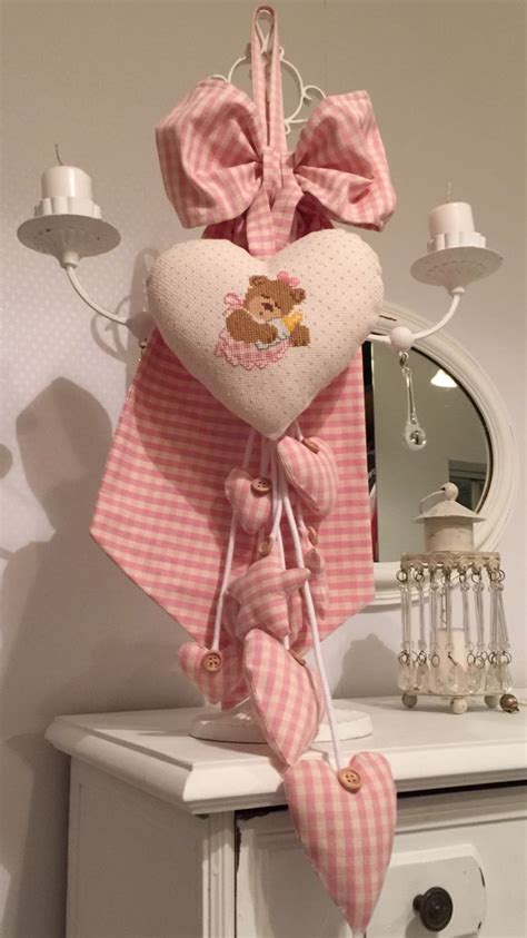 a teddy bear heart hanging from the side of a dresser with pink gingham