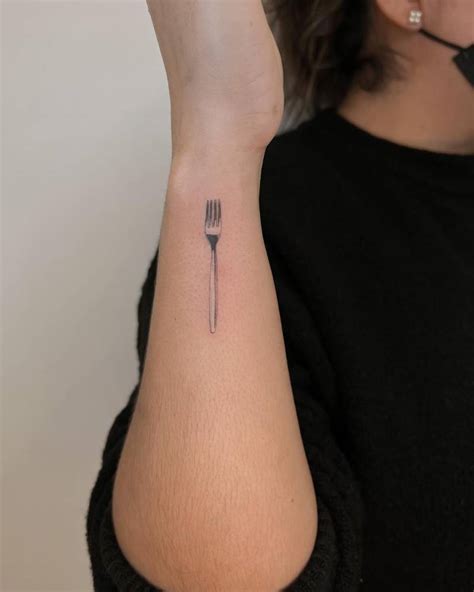 Micro-realistic fork tattooed on the wrist.