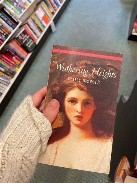 a person holding up a book in front of bookshelves at a bookstore called wuthering heights