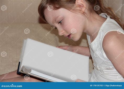 A Girl Reads a Book. a Child Studies a Book on a Beige Bed Stock Photo ...