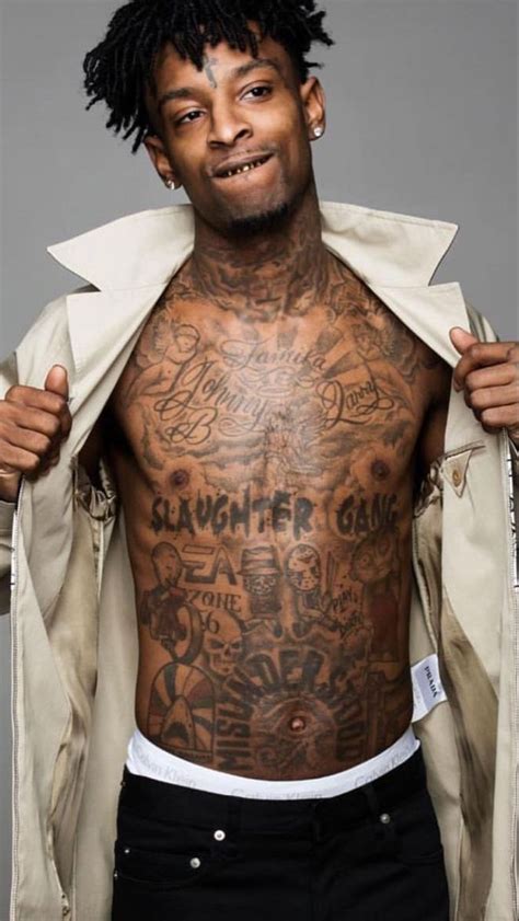 a man with tattoos on his chest and jacket over his shoulder is posing for the camera