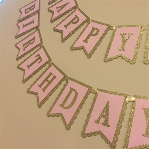 a pink and gold happy birthday banner on a wall