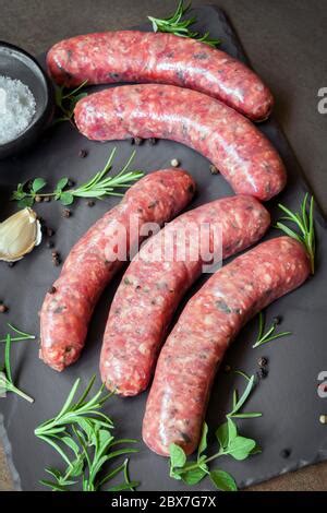 Raw sausages with spices and rosemary on cutting board, white background, top view. Cooking ...