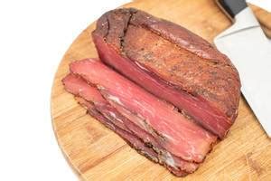 Smoked cured meats on wooden round kitchen board with fork - Creative Commons Bilder