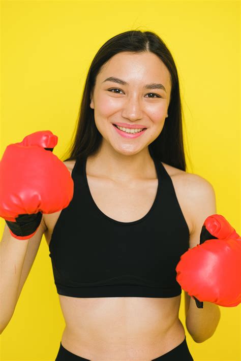 A Woman in Activewear Standing Near Wooden Shelves with Boxing Gloves · Free Stock Photo