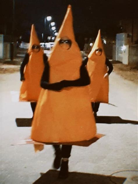 three people in orange costumes are walking down the street at night ...