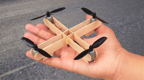 a hand holding a small wooden toy with propellers