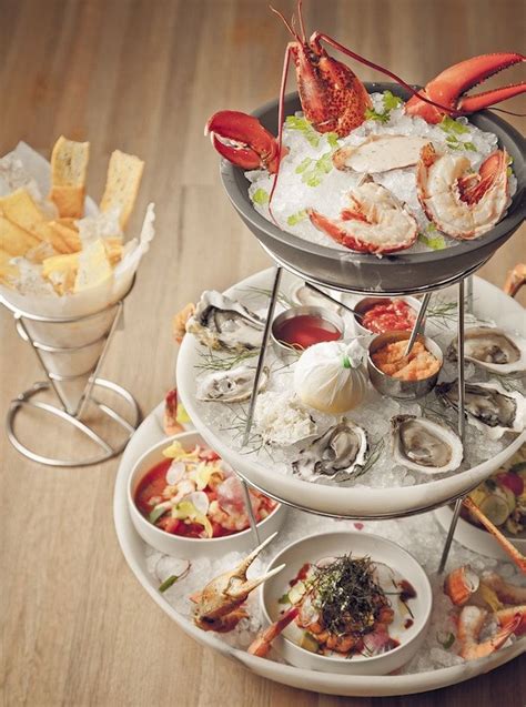 three tiered trays filled with different types of seafood and appetizers on wooden table