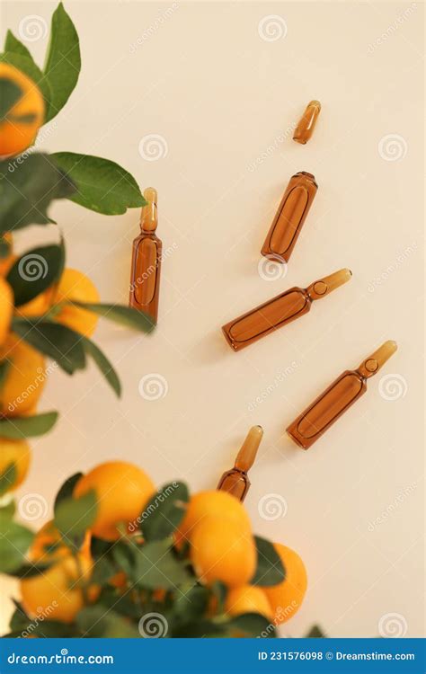 Vitamin C. Glass Ampoules and Tangerine Fruit Bushes on Beige Background.ampoules and Serum with ...
