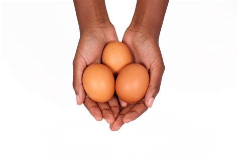 Hands holding three pastured eggs
