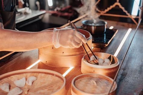 Person Preparing Dumplings Using Chopsticks on Bamboo Steamer · Free ...