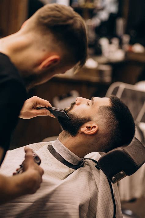 Free Photo | Man at a barbershop salon doing haircut and beard trim ...