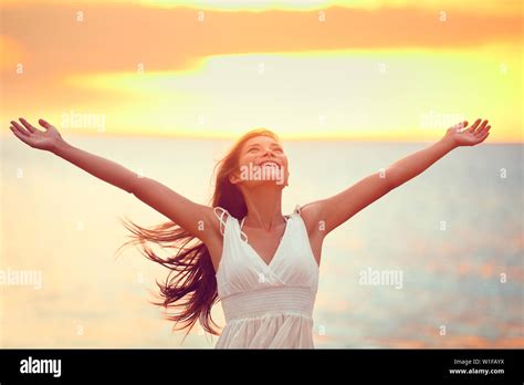 Free happy woman arms up praising freedom at beach sunset. Young adult enjoying breathing freely ...