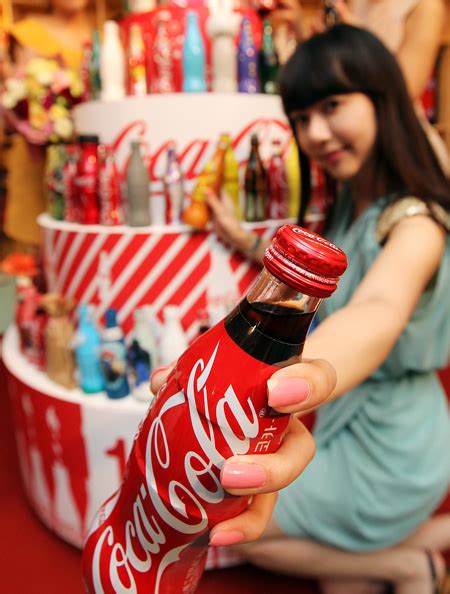 Models flank a Coca-cola bottle in celebration of the 125th anniversary - The Korea Times