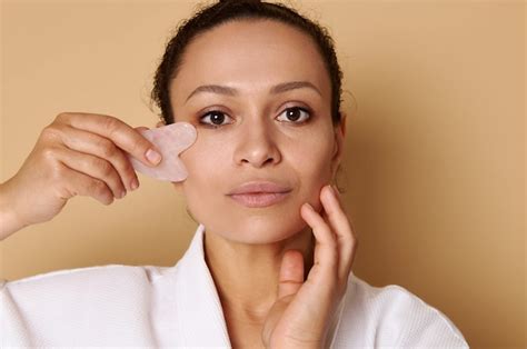 Premium Photo | Beauty portrait of mixed race woman using gua-sha for lymphatic drainage facial ...
